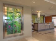 Wall Art/Mirror, Front Desk, and Large Window With Open Blinds in Lobby