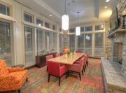 Windows With Open Blinds to Night View, Table, Chairs, TV and Fireplace Lobby Area