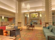 Tables, Soft Seating, Long Drapes, Decorative Lighting, Beverage Stations, Wall Art Above Fireplace, and View of Front Desk in Lobby