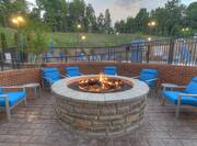 Six Blue Armchairs Around Lit Fire Pit and View of Pool at Dusk