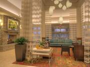 Tables, Soft Seating, Long Drapes, Decorative Lighting, Beverage Station, and Wall Art Above Fireplace in Lobby
