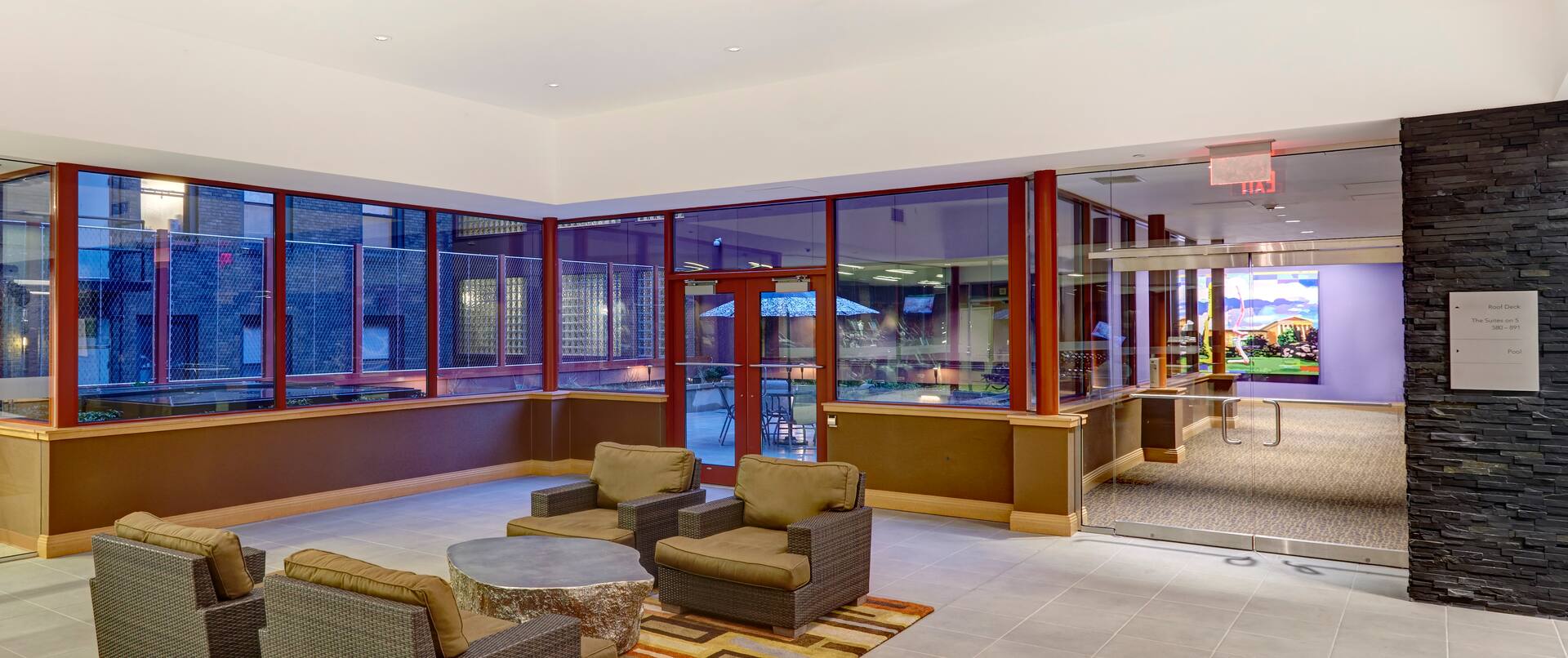 Soft Seating, Metallic Table, and Large Windows With Patio View at Sunset in Suites on 5 Lobby