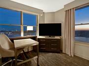 guest room with work desk television and windows with a view