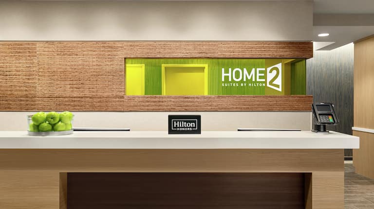 Welcoming front desk in lobby with Hilton Honors sign and green apples.