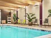 Beautiful indoor pool featuring patio furniture, lush plants, and complimentary towels.