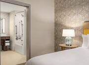 Private bedroom in accessible suite featuring comfortable king bed and en-suite bathroom.