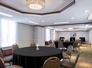 Banquet and Cocktail Tables With Black Linens, Chairs, Windows With Sheer Drapes, and Wall Art in Meeting Room