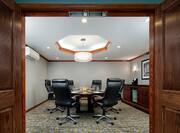 Open Wooden Doors to Meeting Room With Seating For Six at Table and Wall Art