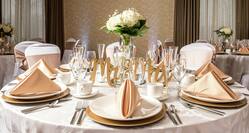 Close up of Place Settings, Flowers, Candles, and White Linens on Round Table Decorated for a Wedding Reception