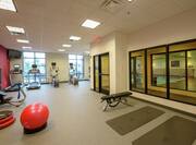 Fitness Center With TV, Cardio Equipment, Weight Bench, View Into Indoor Pool, Red Stability Ball, Aerobic Stepper, and Water Cooler