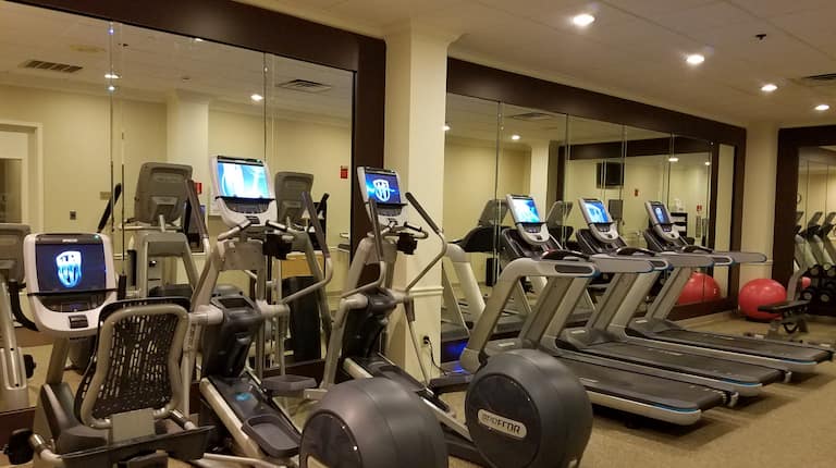 Cardio Equipment Facing Mirrored Wall and Red Exercise Ball in Fitness Center