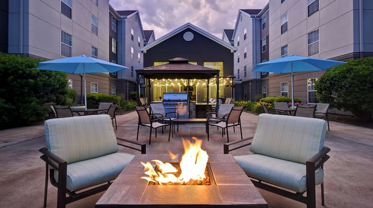 exterior patio with seating firepits and barbeques at dusk
