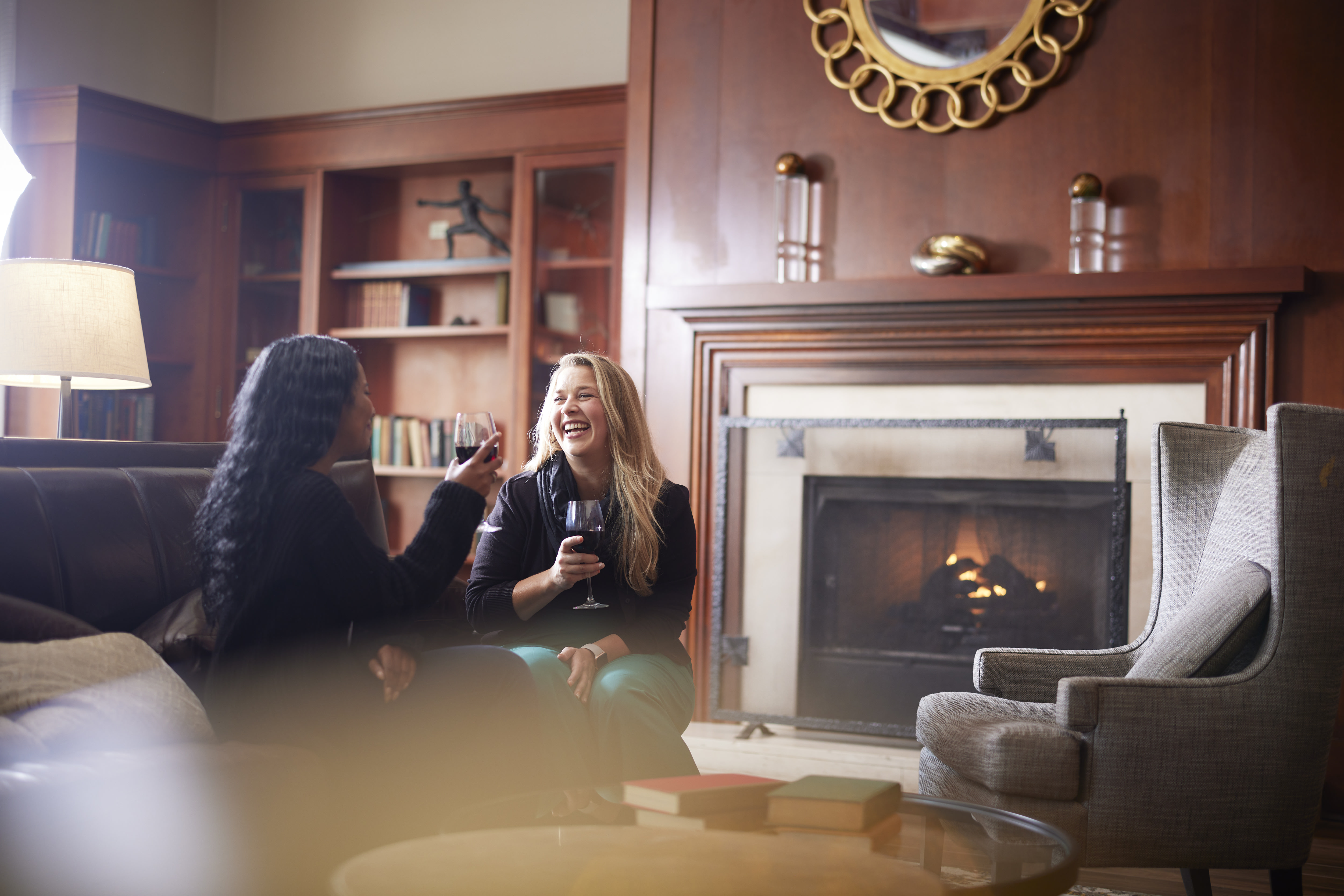 two women having drinks by fireplace