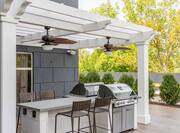 Outdoor patio with BBQ grills and attached dining table with chairs under pavilion