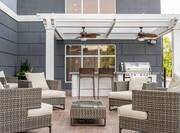 Outdoor patio with lounge chairs, coffee table, and BBQ grills with attached dining table and chairs, under pavilion