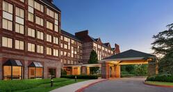 Welcoming Embassy Suites hotel featuring porte cochere, glowing guestroom windows, and beautiful dusk sky.