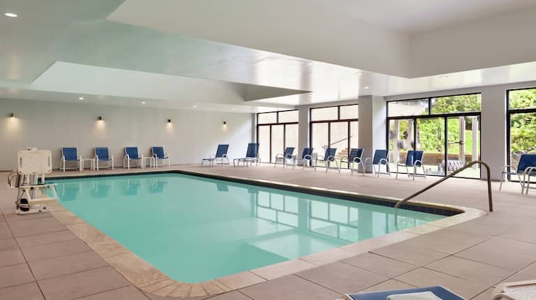 Beautiful indoor pool featuring large windows, ample seating, and accessible chair lift.