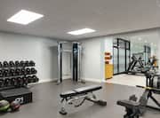 Spacious on-site fitness center featuring cardio machines, free weights, and work out benches.