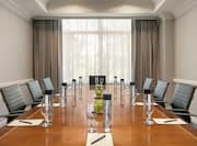 Bright meeting room featuring large boardroom table, notepads and pens, and complimentary beverage.