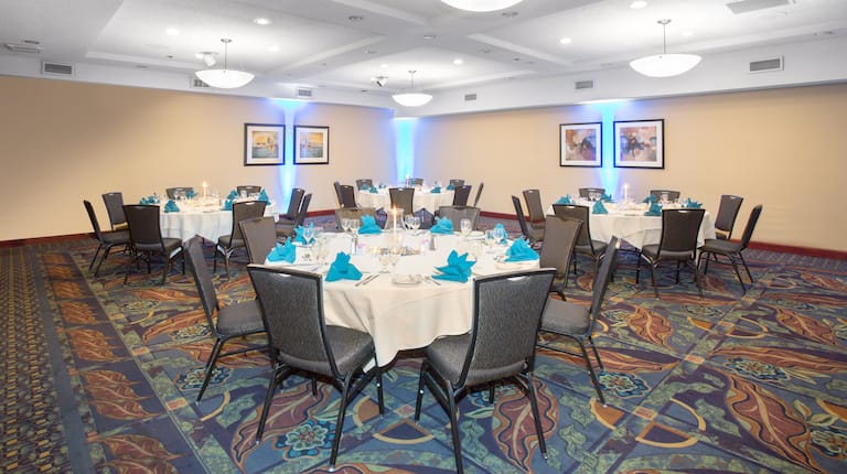 Cena social en la sala de reuniones con cuatro mesas redondas grandes con montaje en ocho lugares y servilletas azules