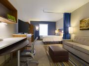 Overview of Living Area, Work Desk, TV and Queen Bed in Studio Suite 