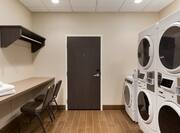 Guest Use Laundry Room With Folding Table and Two Chair, Entry Door, Coin Operated Washing and Drying Machines, 