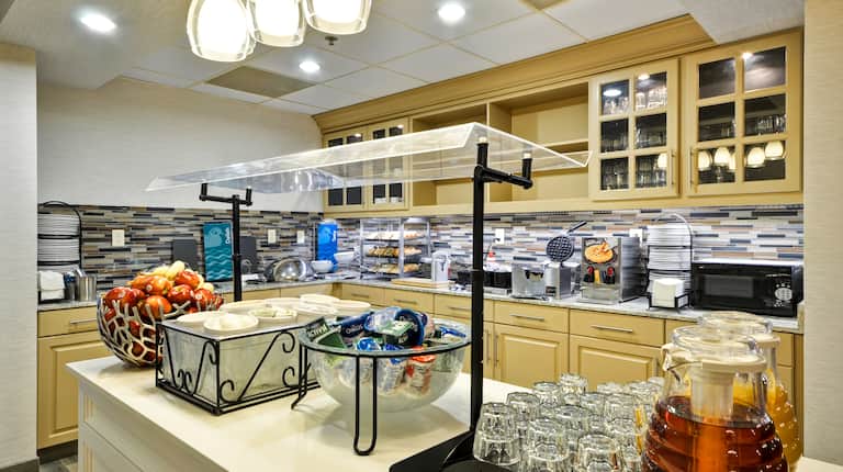 Breakfast serving area with coffee, juice, fruit, cereals, and dining amenities