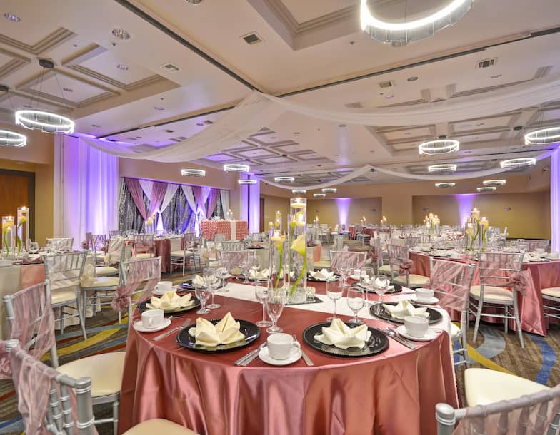 A large ballroom with tables, chairs and table settings