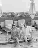 Pria dan wanita duduk dengan kaki di kolam renang