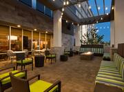 Outdoor Patio With Cushioned Armchairs and Striped Sofas by Rectangular Fire Pit at Night
