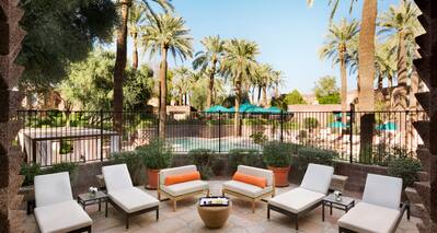 Two Chairs and Four Loungers on Presidential Suite Patio With Pool View Surrounded by Palm Trees 