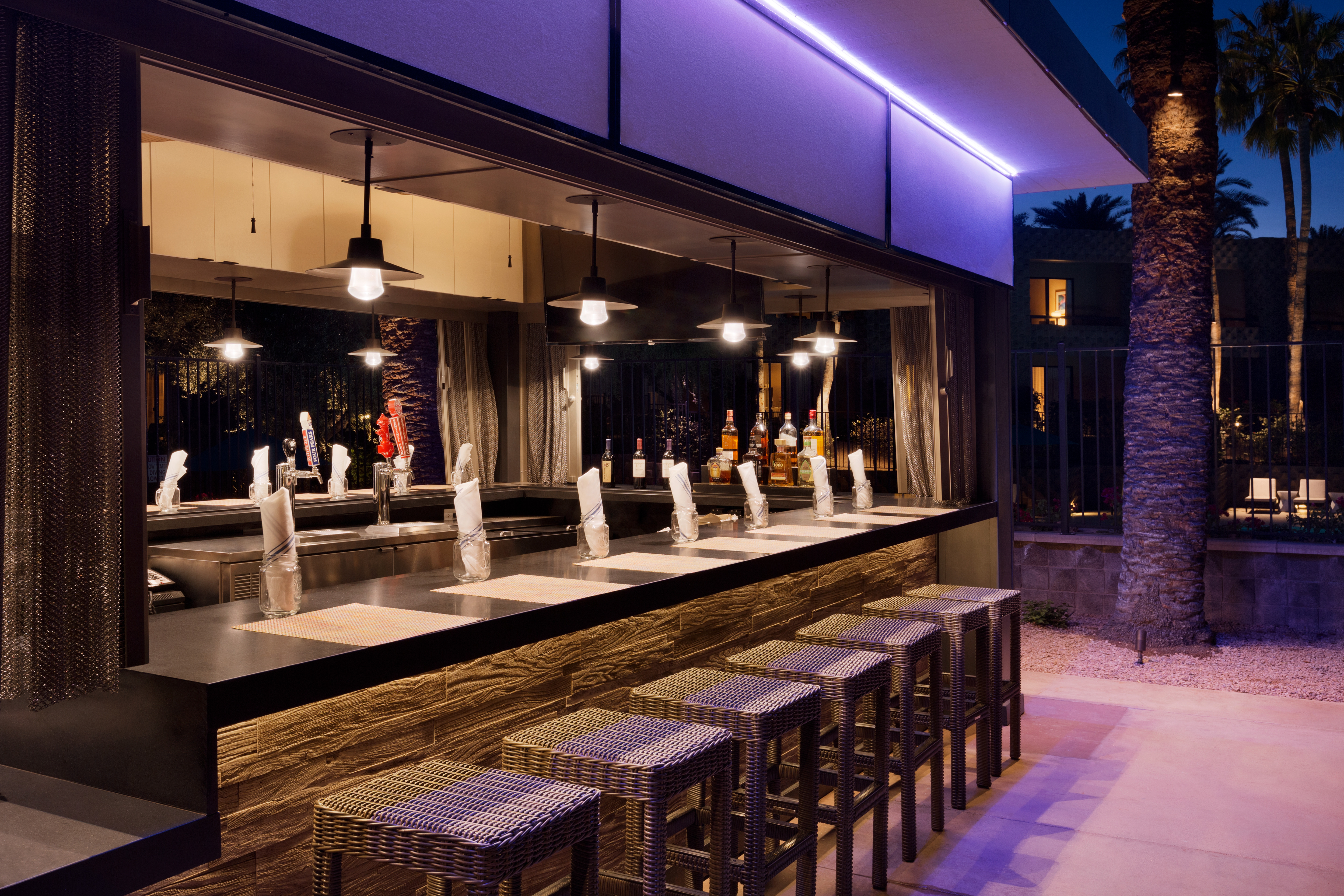 Illuminated Counter Seating at Azure Pool Bar Surrounded by Palm Trees at Night