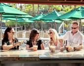 Three Women and a Man Enjoying Drinks Outside at Bar