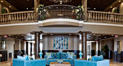 Lobby Lounge With Art Feature, Teal Seating, Tables, Chandelier, and View of Second Floor Railing