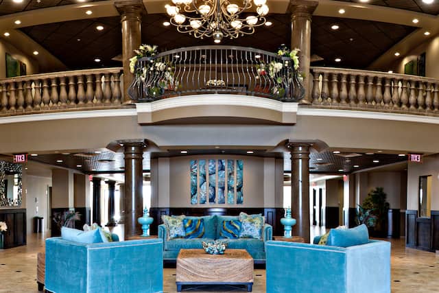 Lobby Lounge With Art Feature, Teal Seating, Tables, Chandelier, and View of Second Floor Railing