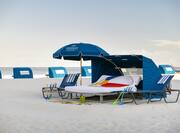 Beach umbrella and cabana with two lounge chairs, ocean in background