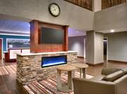 Lobby Lounge Area Near Front Desk With Fireplace, Flat Screen TV, Couch, and Tables