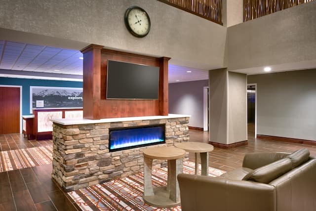 Lobby Lounge Area Near Front Desk With Fireplace, Flat Screen TV, Couch, and Tables