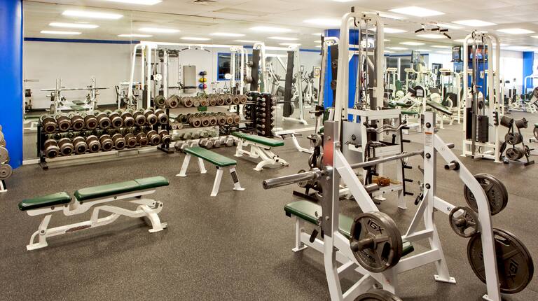Fitness Center With Benches, Weight Machines, Mirrored Wall, Free Weights, and Weight Balls