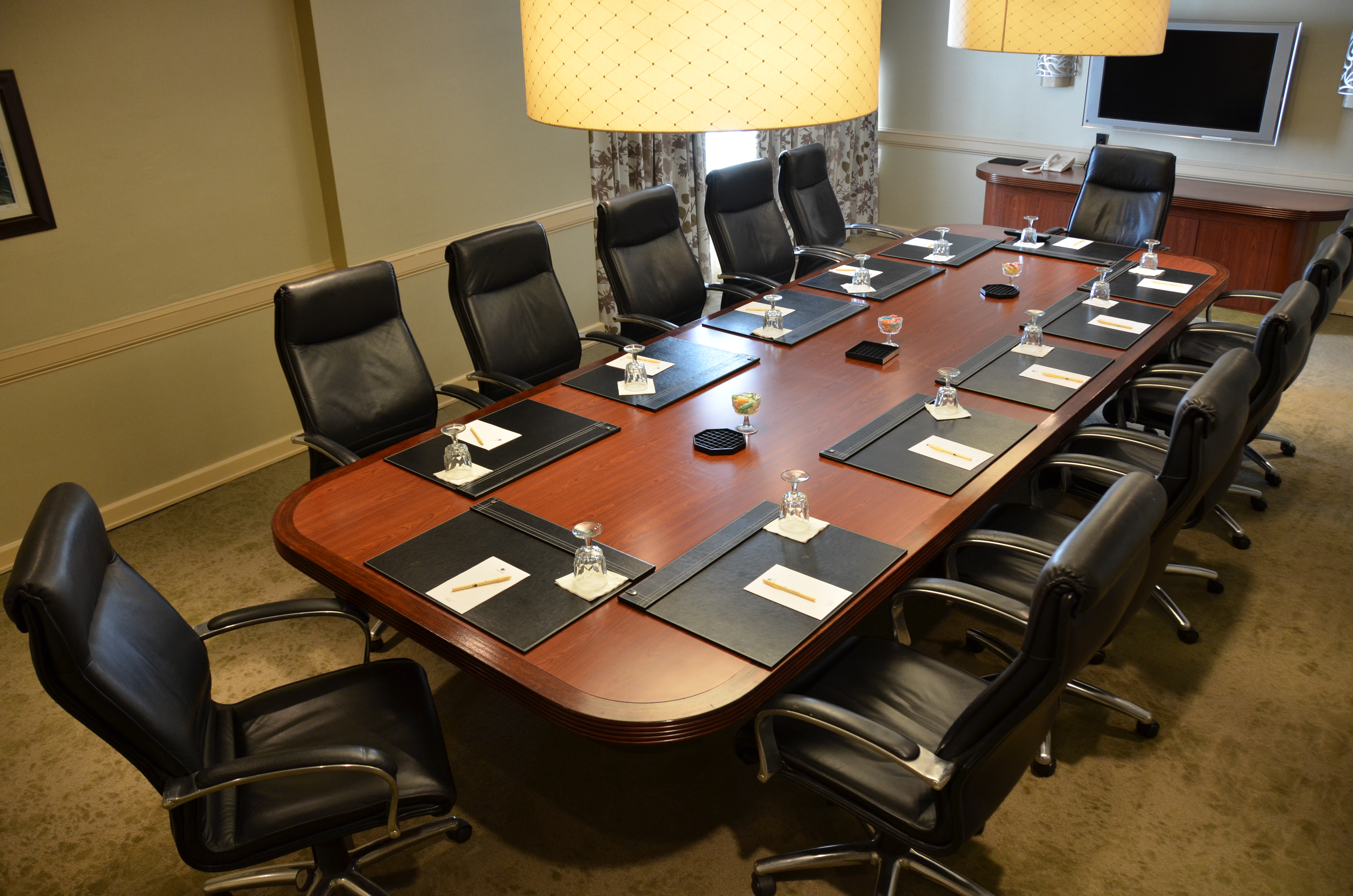 Drinking Glasses, Notepads, and Seating for 12 at Boardroom Table, Wall Art, Window With Open Drapes, and TV