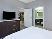 Guest Room with King sized Bed and TV and Partial View of Kitchen and Bathroom Areas