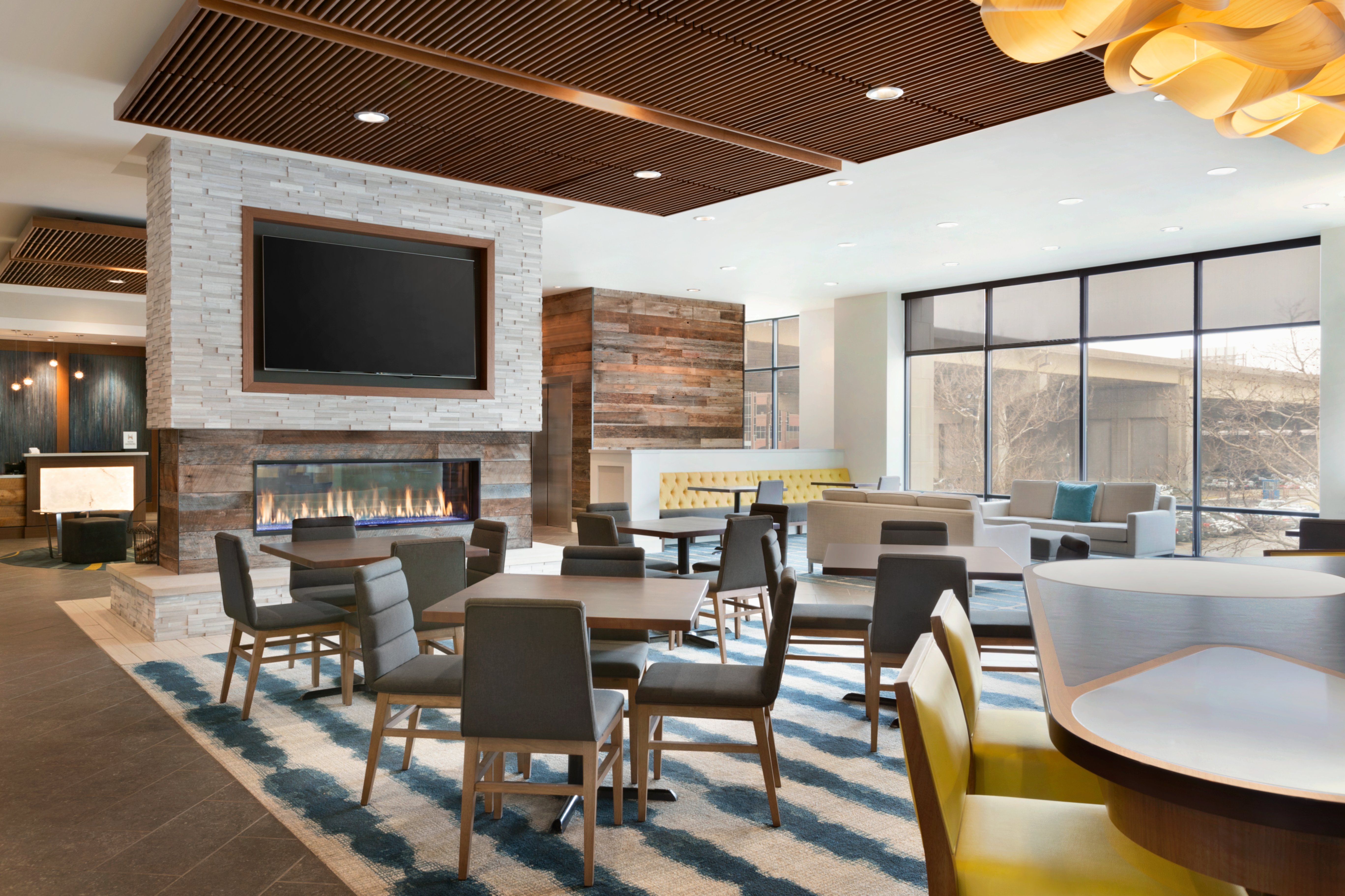Lobby Seating Area with dining tables, TV, fire place, and windows with outdoor view