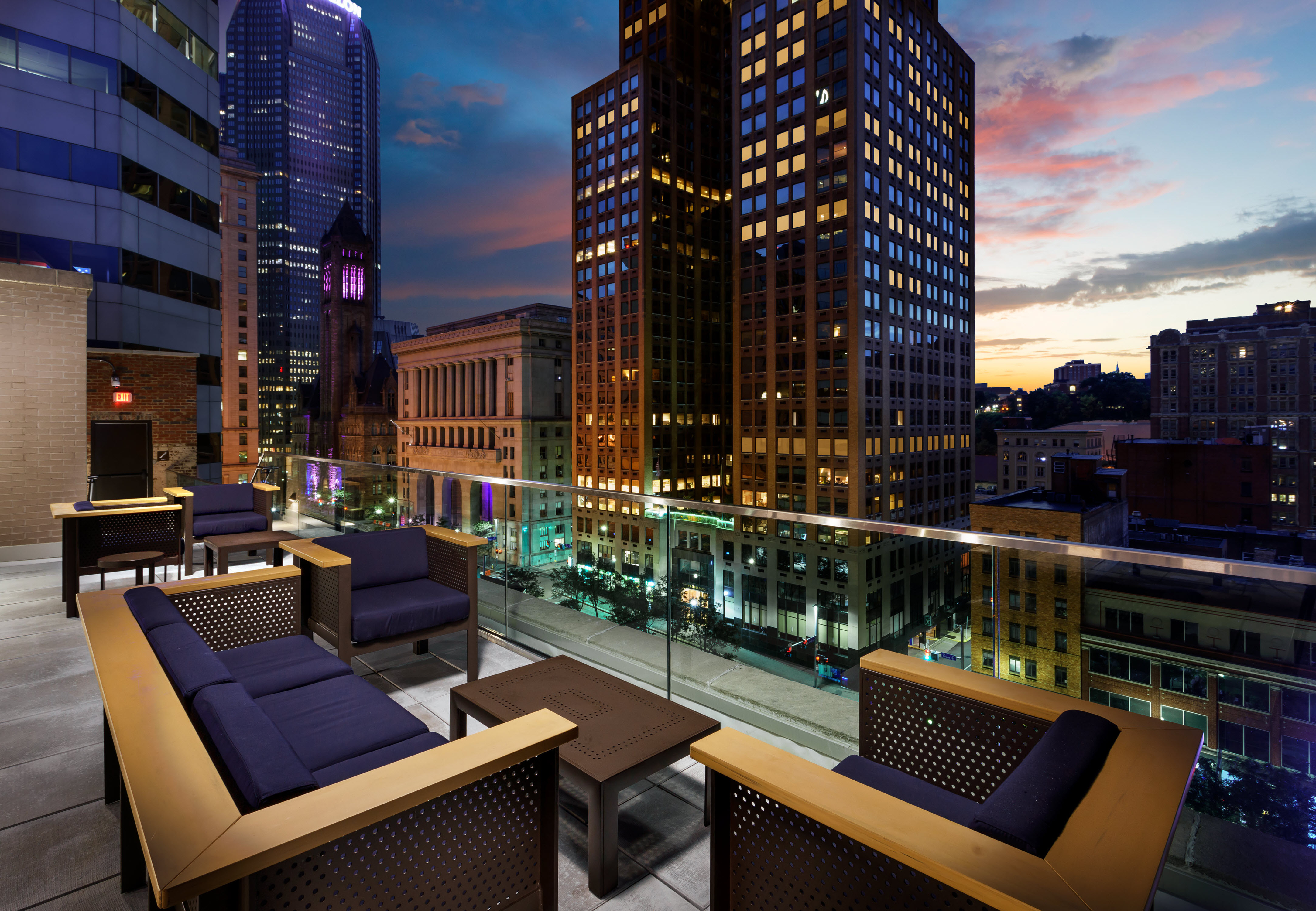 Hotel Rooftop Terrace Seating Area with Armchairs, Sofa and Coffee Table at Dusk