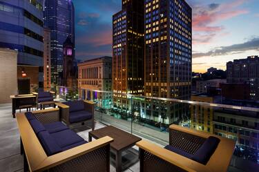 Hotel Rooftop Terrace Seating Area with Armchairs, Sofa and Coffee Table at Dusk