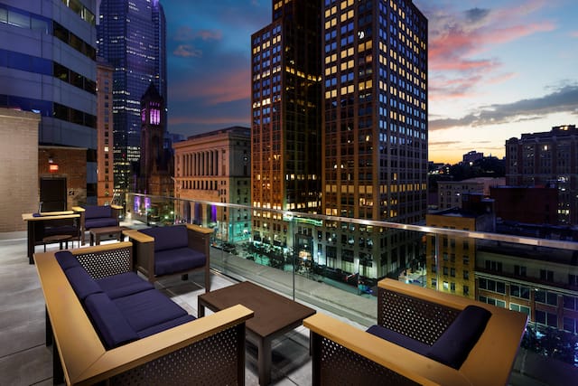 Hotel Rooftop Terrace Seating Area with Armchairs, Sofa and Coffee Table at Dusk