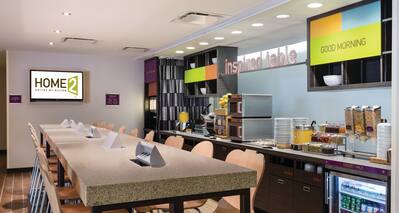 TV, Community Table With Chairs, and Brightly Lit Food Service Area of Inspired Table