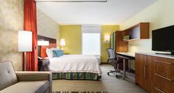 TV, Sofa, Floor Lamp by Orange Partition Curtain, King Bed, Lamps on Bedside Table, Window, and Work Desk in Studio Suite