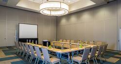 Meeting Room With Water Bottles and Bowls of Green Apples on U-Shaped Table, Chairs, Projector Table, and Presentation Screen