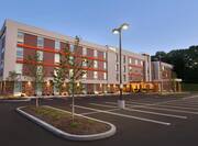 Angled View of Hotel Parking Lot, Landscaping, and Exterior Illuminated at Dusk
