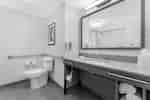 Baño accesible para personas con discapacidades con barras de apoyo y espejo grande